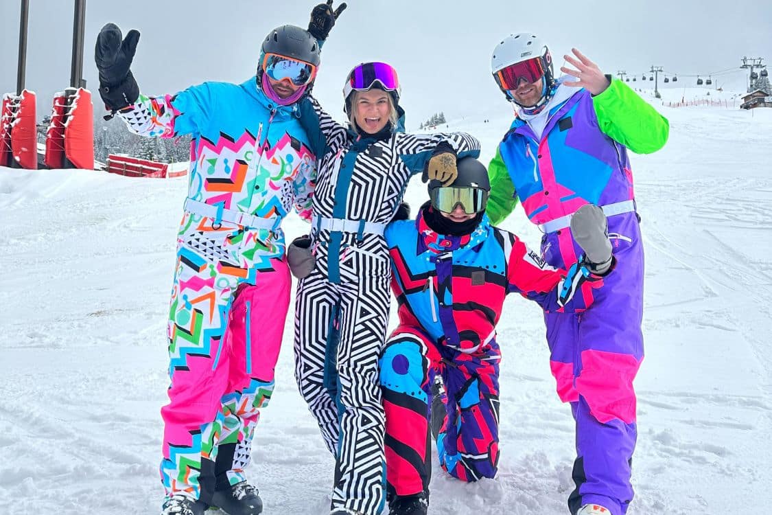 A group of people in colorful OOSC ski suits posing for a photo.