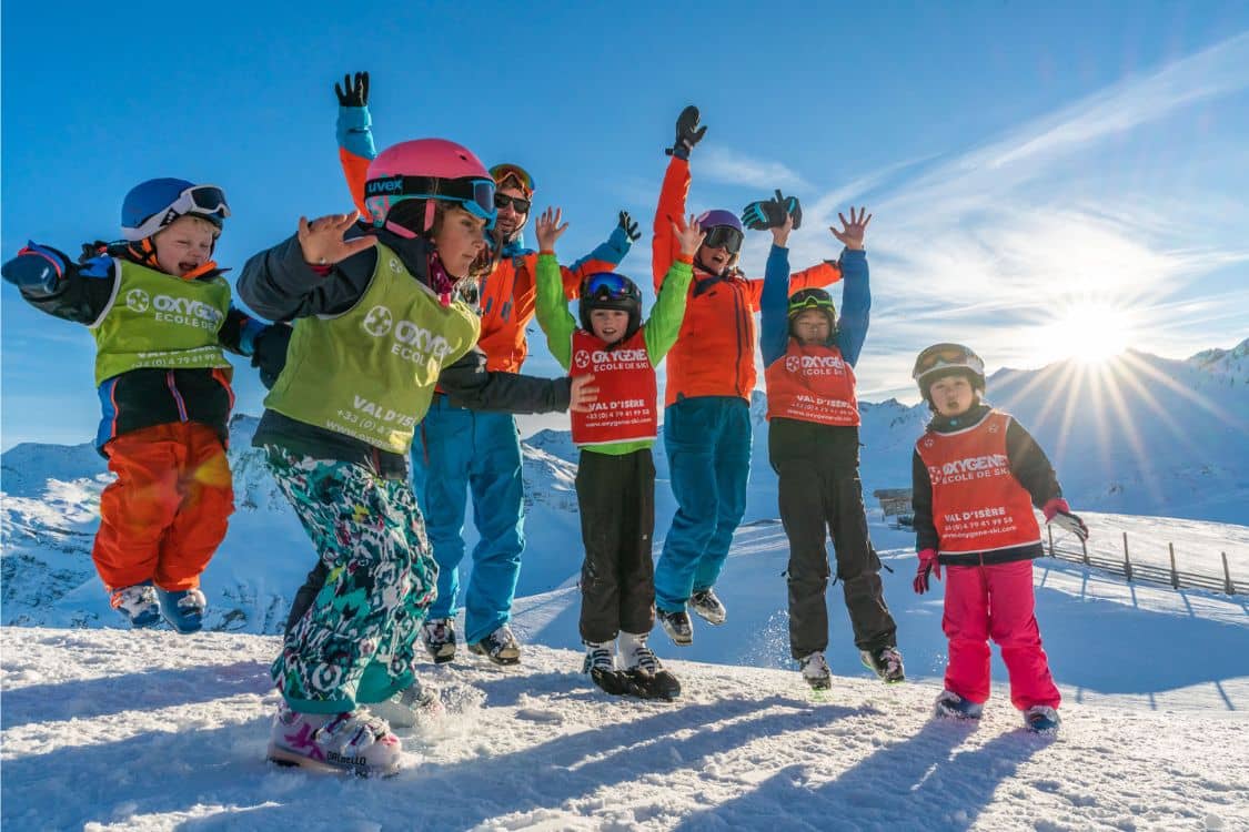 A group of children in ski gear on a snowy slope.
