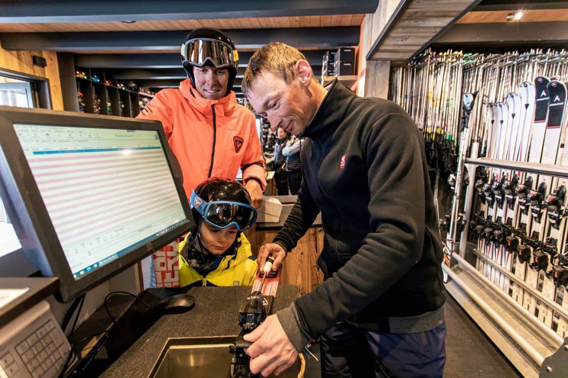 A group of people looking at ski equipment in a store.