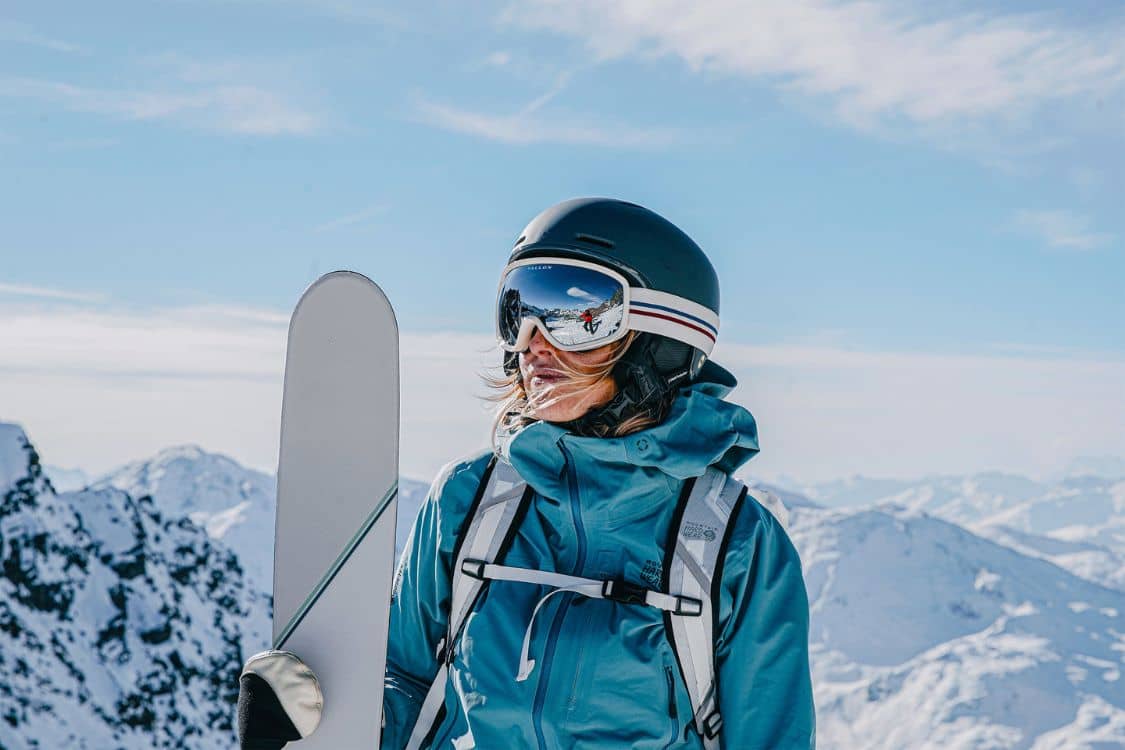 A woman holding skis on top of a mountain.